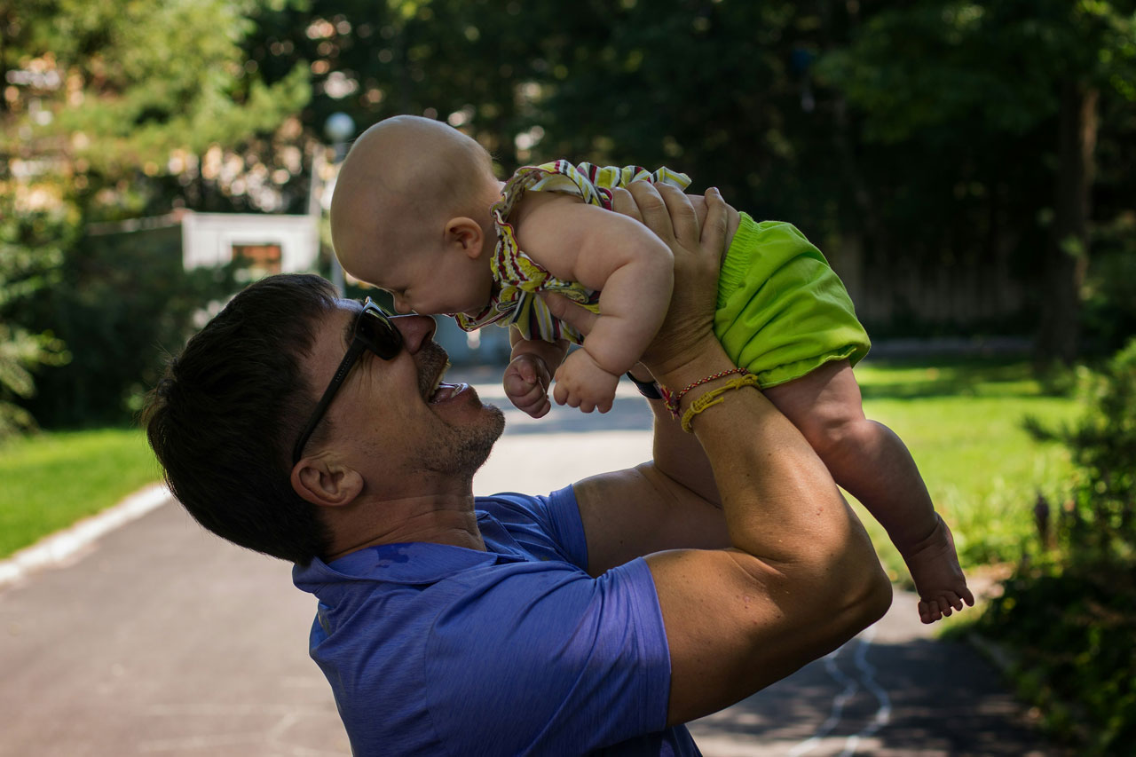 A man holding up his granddaughter and smiling